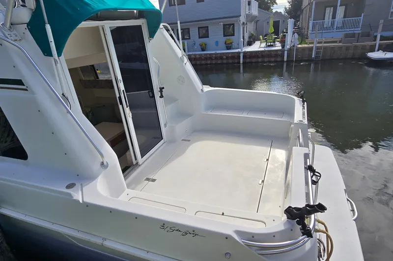 Slide: The Image of 1995 Mainship 31 Sedan Bridge boat docked, featuring spacious deck and sliding door entry. - 4