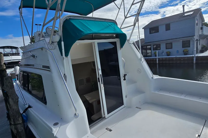 Slide: The Image of 1995 Mainship 31 Sedan Bridge boat docked, featuring a spacious deck and teal canopy. - 5