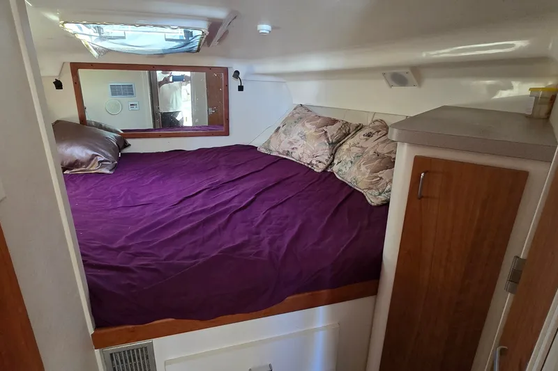 Slide: The Image of 1995 Mainship 31 Sedan Bridge cabin with purple bedding and wooden cabinetry. - 25