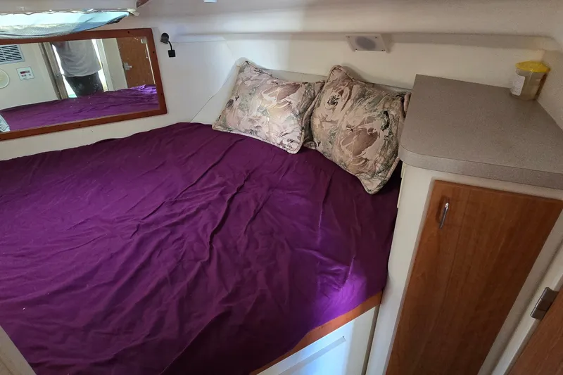 Slide: The Image of Cozy cabin interior of 1995 Mainship 31 Sedan Bridge with purple bedding and floral pillows. - 27