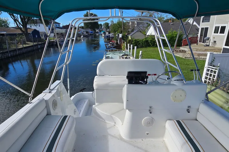 Slide: The Image of 1995 Mainship 31 Sedan Bridge boat on a serene canal, featuring a spacious deck and seating. - 8