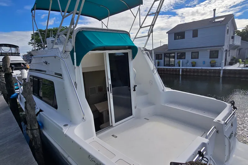 Slide: The Image of 1995 Mainship 31 Sedan Bridge docked, featuring spacious deck and teal canopy. - 3
