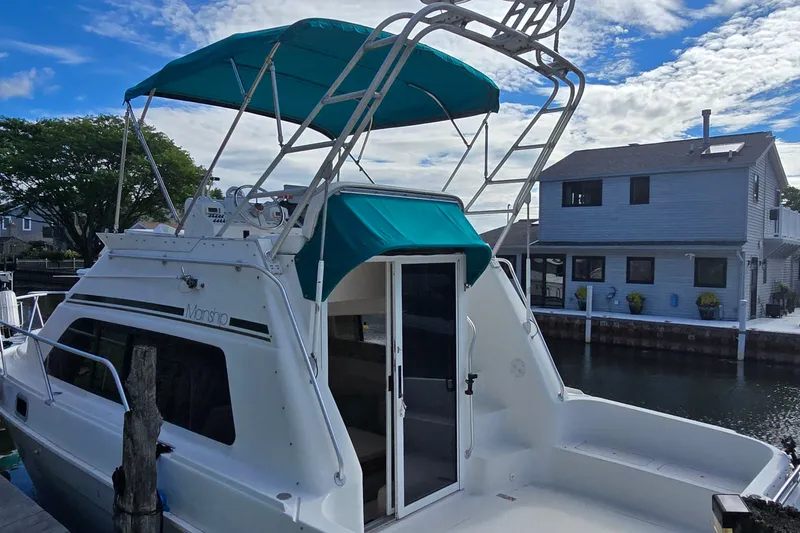 Slide: The Image of 1995 Mainship 31 Sedan Bridge boat docked near waterfront homes. - 2