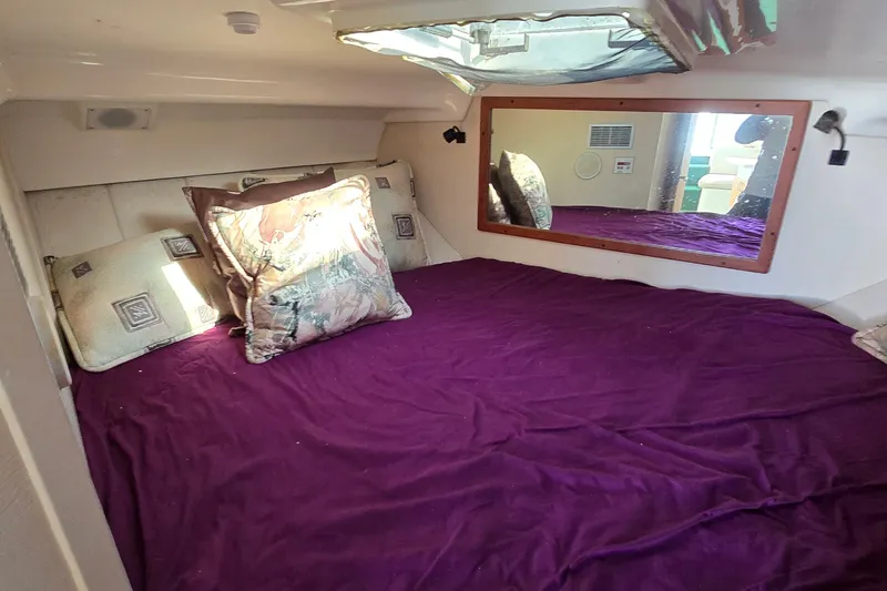 Slide: The Image of Cozy cabin interior of 1995 Mainship 31 Sedan Bridge with purple bedding and decorative pillows. - 26