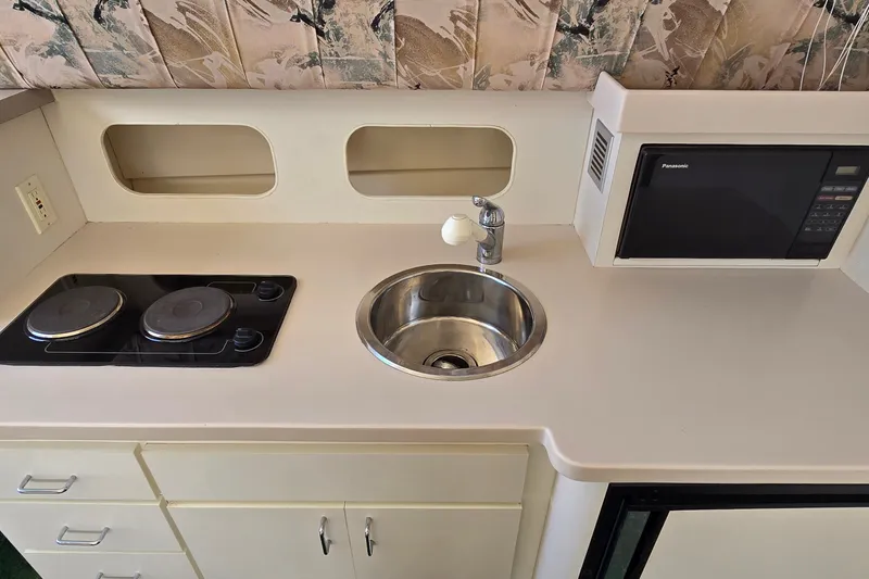 Slide: The Image of Compact kitchen area in a 1995 Mainship 31 Sedan Bridge with stove, sink, and microwave. - 20