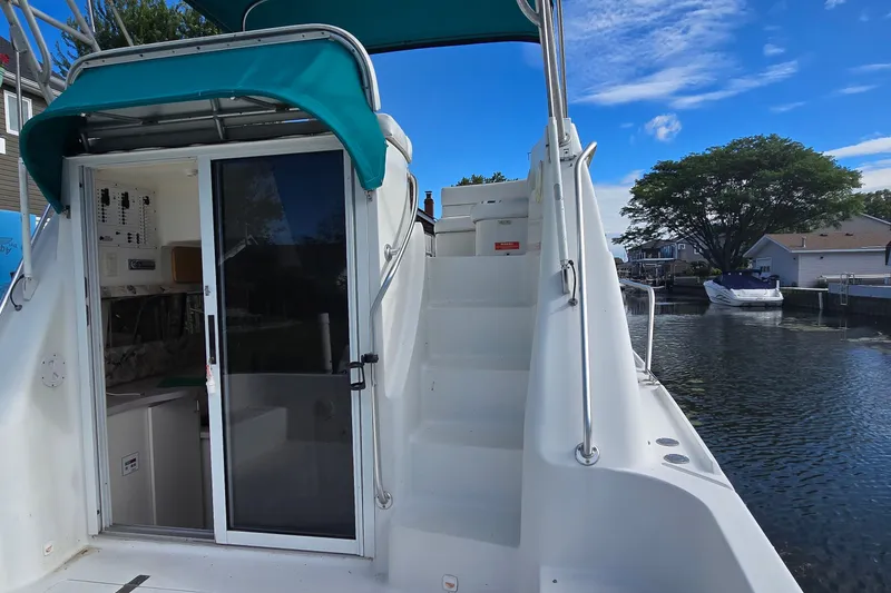 Slide: The Image of 1995 Mainship 31 Sedan Bridge boat with open cabin door and stairs, docked by water. - 6