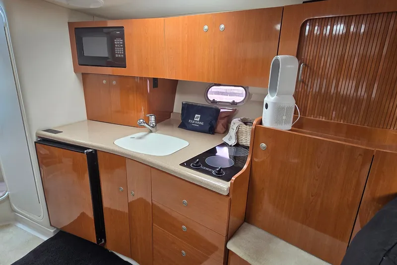 Slide: The Image of 2000 Four Winns 328 Vista yacht kitchen with microwave, sink, and wooden cabinetry. - 20