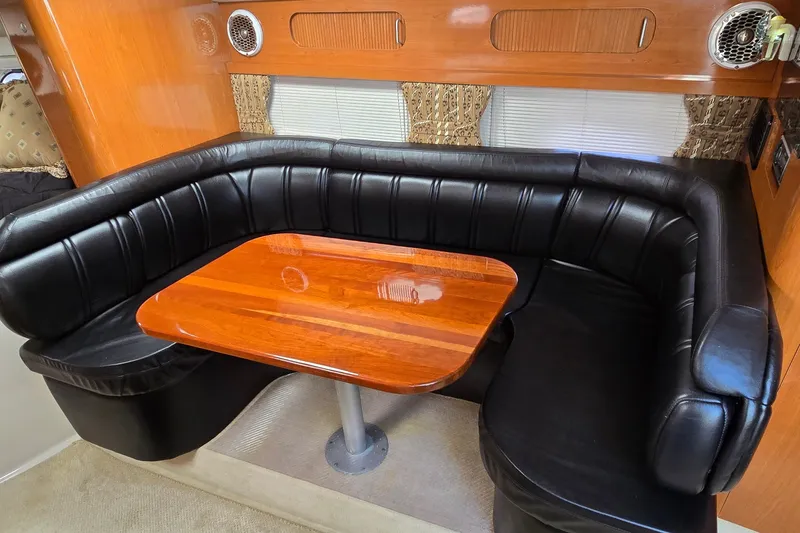 Slide: The Image of Luxurious interior of 2000 Four Winns 328 Vista with black leather seating and wooden table. - 23