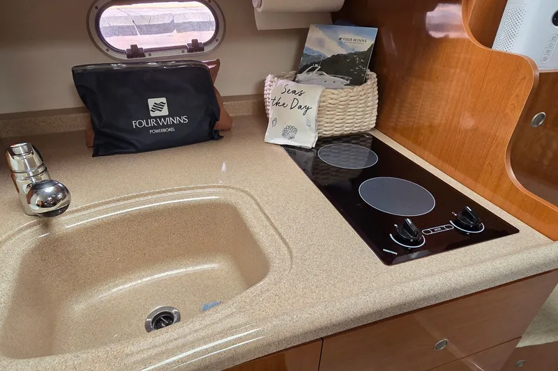 Slide: The Image of 2000 Four Winns 328 Vista kitchen with sink, electric stove, and branded accessories. - 21