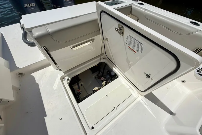 Slide: The Image of 2022 Pursuit DC 266 Dual Console boat storage compartment open, revealing interior components. - 16