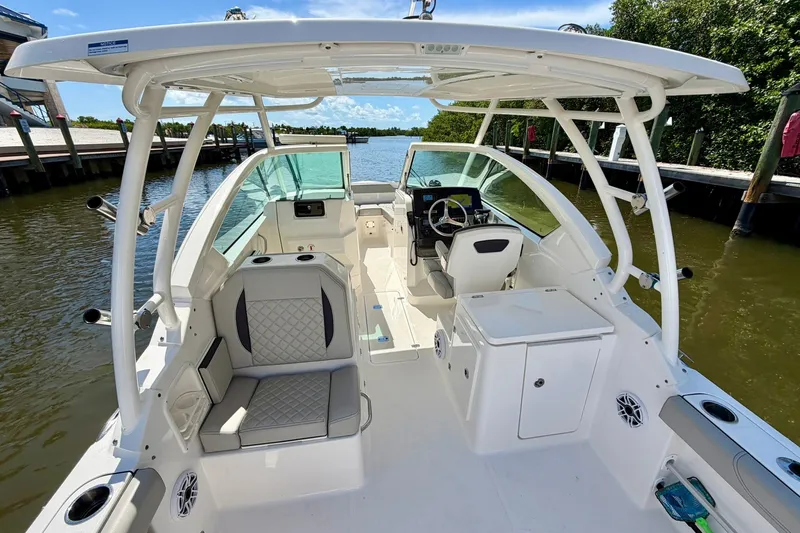 Slide: The Image of 2022 Pursuit DC 266 Dual Console boat interior with seating and helm, docked by the water. - 19