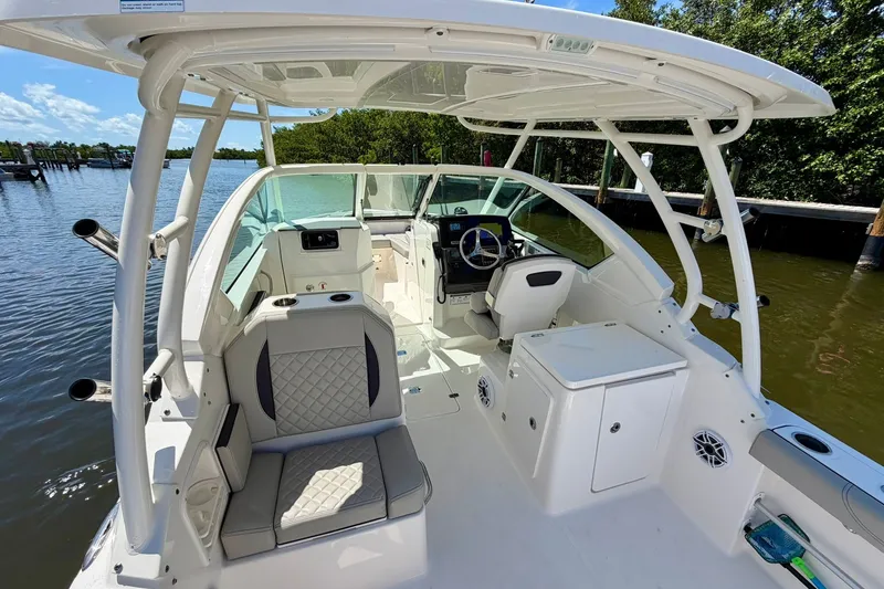 Slide: The Image of 2022 Pursuit DC 266 Dual Console boat interior with seating and helm, docked by water. - 20
