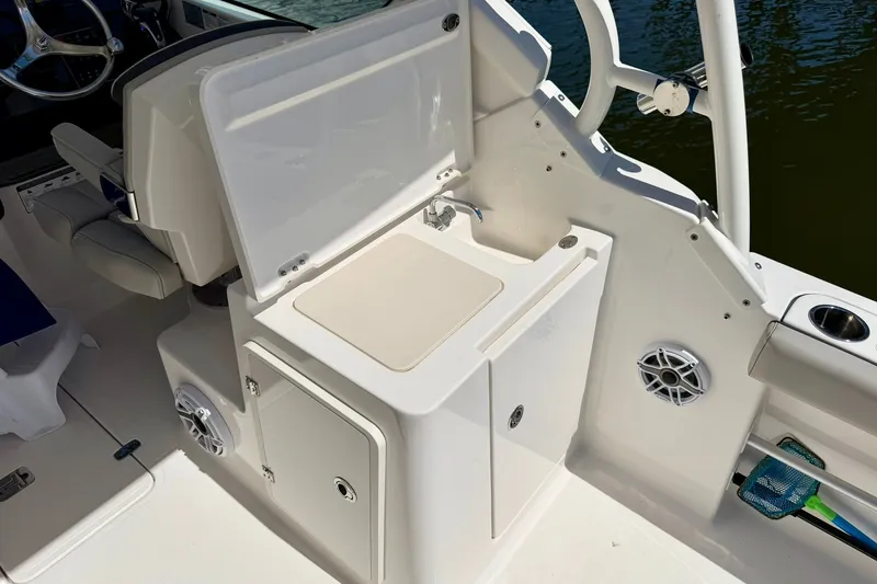 Slide: The Image of 2022 Pursuit DC 266 Dual Console boat interior with sink and storage area. - 21