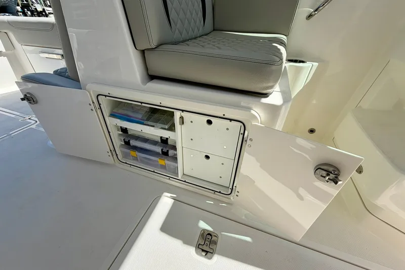 Slide: The Image of 2022 Pursuit DC 266 Dual Console boat storage compartment with organized tackle boxes. - 29