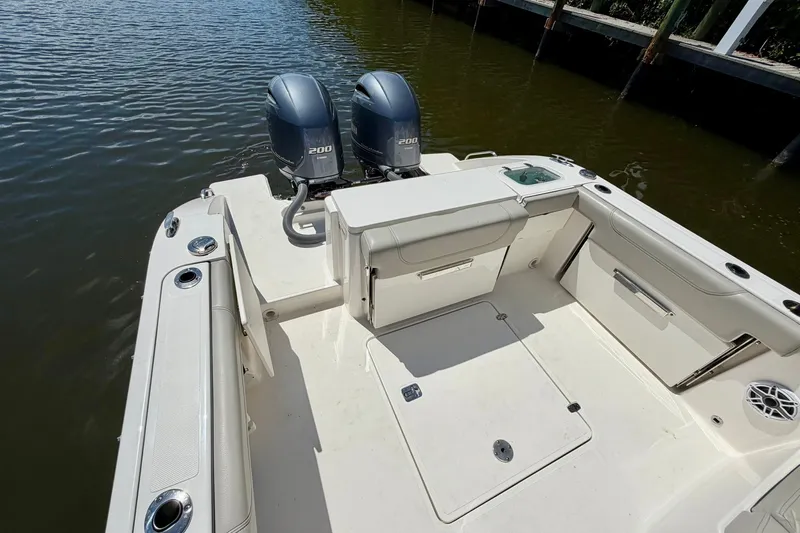 Slide: The Image of 2022 Pursuit DC 266 Dual Console boat with twin 200 engines, docked on calm water. - 14