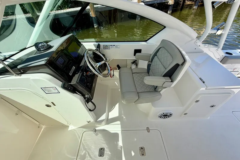 Slide: The Image of 2022 Pursuit DC 266 Dual Console boat interior with helm, steering wheel, and cushioned seat. - 24