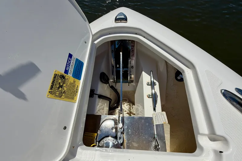 Slide: The Image of Anchor compartment of 2022 Pursuit DC 266 Dual Console boat, open with visible chain and warnings. - 39