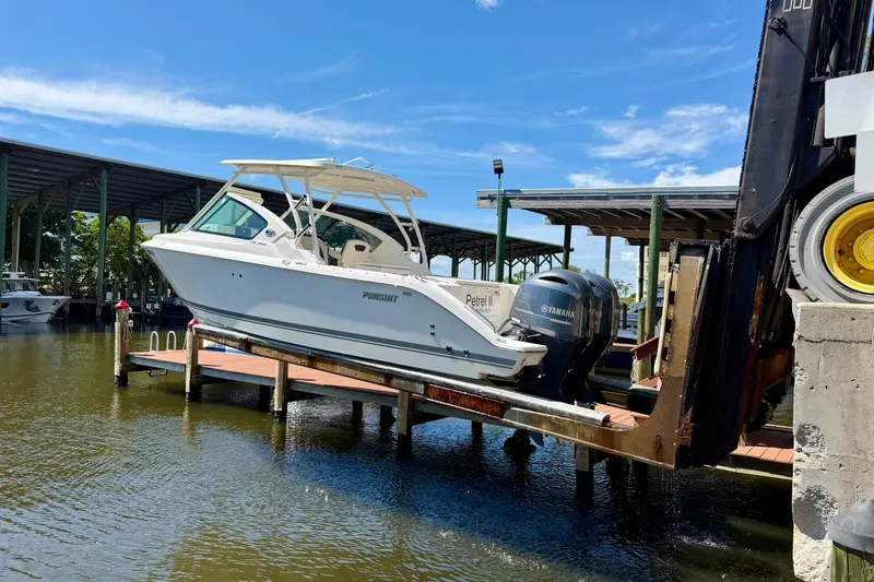 Slide: The Image of 2022 Pursuit DC 266 Dual Console boat being lifted at a marina dock. - 40