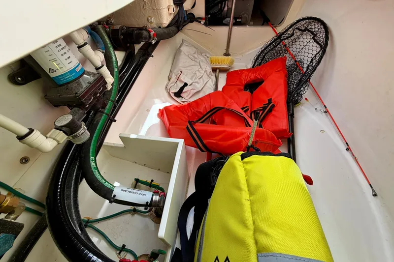 Slide: The Image of Storage compartment of 2022 Pursuit DC 266 boat with life jackets and fishing gear. - 31
