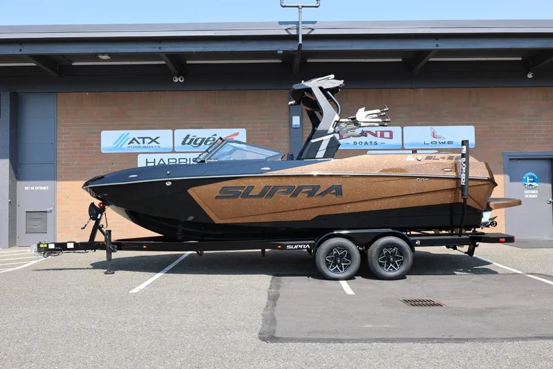 Slide: The Image of Ein Supra SL 550 Boot von 2026 steht auf einem Anhänger vor einem Gebäude. - 2