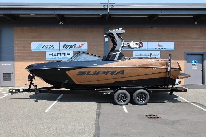 The Image of Ein Supra SL 550 Boot von 2026 steht auf einem Anhänger vor einem Gebäude. - 1