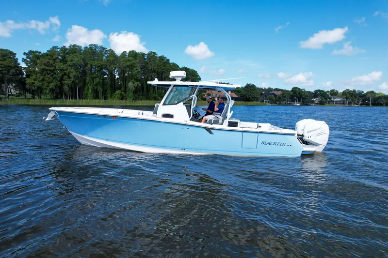 Slide: The Image of 2023 Blackfin 332 CC boat cruising on a serene lake under a clear blue sky. - 1