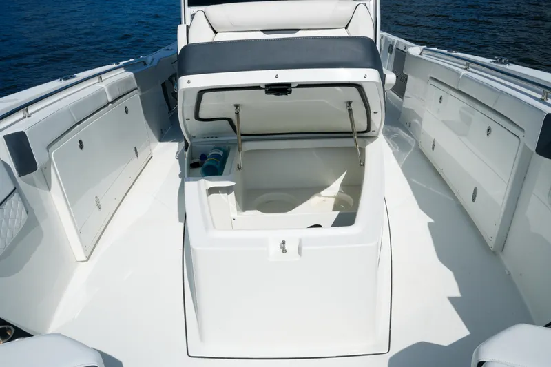 Slide: The Image of 2023 Blackfin 332 CC boat interior with open storage compartment, white seating, and ocean backdrop. - 16