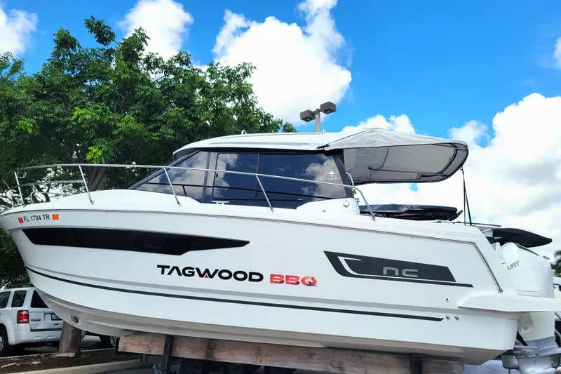 Slide: The Image of 2023 Jeanneau NC 895 boat with canopy, parked outdoors under blue sky. - 0
