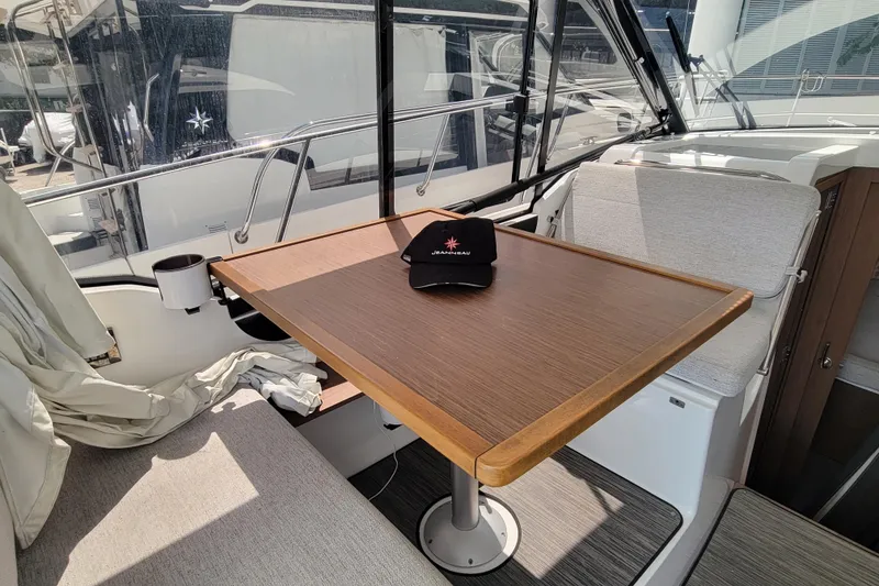 Slide: The Image of 2023 Jeanneau NC 895 interior with table, seating, and branded cap. - 11