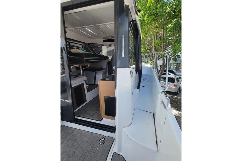 Slide: The Image of 2023 Jeanneau NC 895 boat interior with open door, showcasing modern design and seating. - 7
