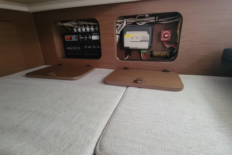 Slide: The Image of 2023 Jeanneau NC 895 interior electrical panel with wooden covers and wiring. - 25