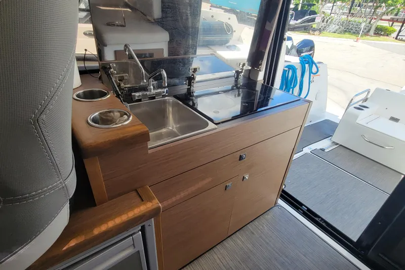 Slide: The Image of 2023 Jeanneau NC 895 boat interior with compact kitchen and sink area. - 15