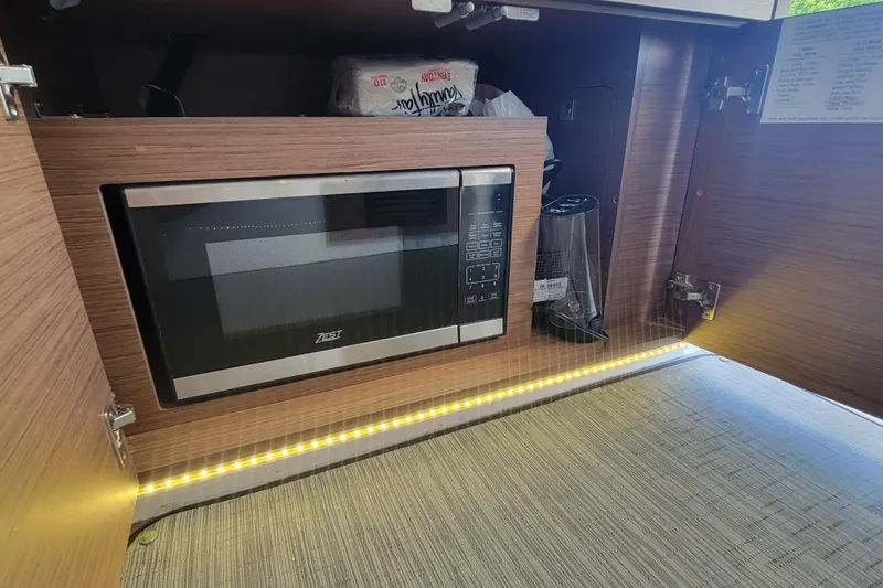 Slide: The Image of Microwave in Jeanneau NC 895 boat kitchen, 2023 model, with wooden cabinetry and LED lighting. - 21