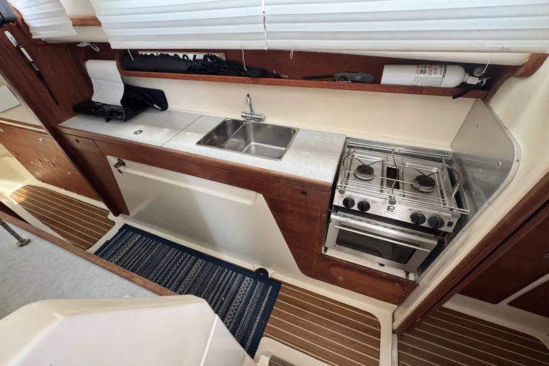 Slide: The Image of Compact kitchen in a 2007 Gemini 105 MC boat with stove, sink, and wooden cabinetry. - 15