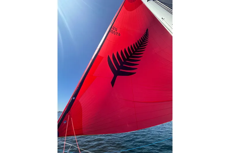 Slide: The Image of Red sail with black fern design on 2024 J Boats J/45 under clear blue sky. - 15