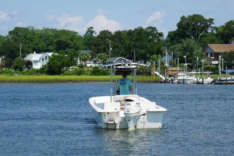 Slide: The Image of 2015 Carolina Skiff 218 DLV boat cruising on a scenic river near waterfront homes. - 5