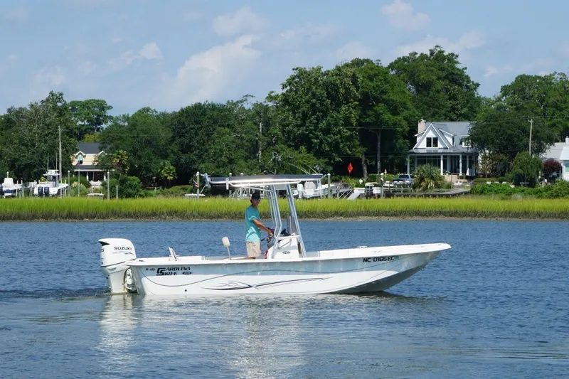Slide: The Image of 2015 Carolina Skiff 218 DLV boat cruising on a scenic river with lush greenery. - 3