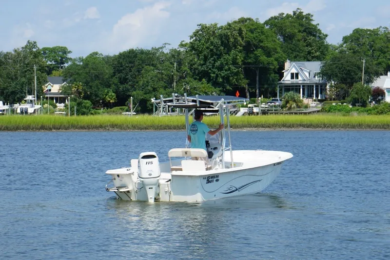 Slide: The Image of 2015 Carolina Skiff 218 DLV boat cruising on a scenic river with lush greenery. - 4