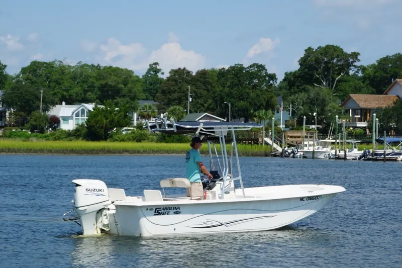 Slide: The Image of 2015 Carolina Skiff 218 DLV boat cruising on a scenic river with lush greenery. - 6