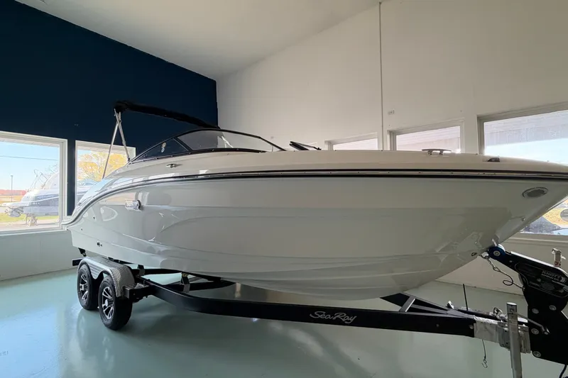 The Image of 2027 Sea Ray SPX 210 boat on trailer in showroom, sleek white design. - 1