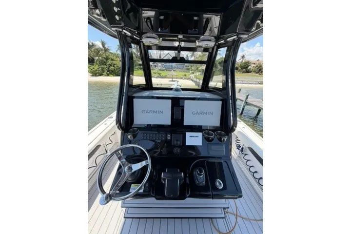 Slide: The Image of 2024 Tidewater 3100 Carolina Bay boat dashboard with dual Garmin displays and steering wheel. - 26