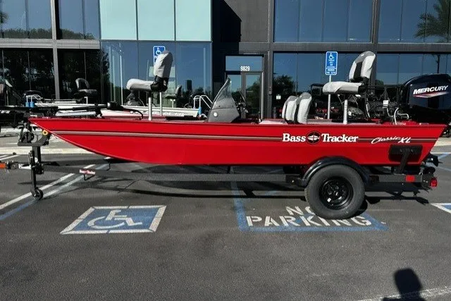 The Image of 2027 Tracker Bass Tracker Classic XL boat in red, parked in a lot with accessible spaces. - 0