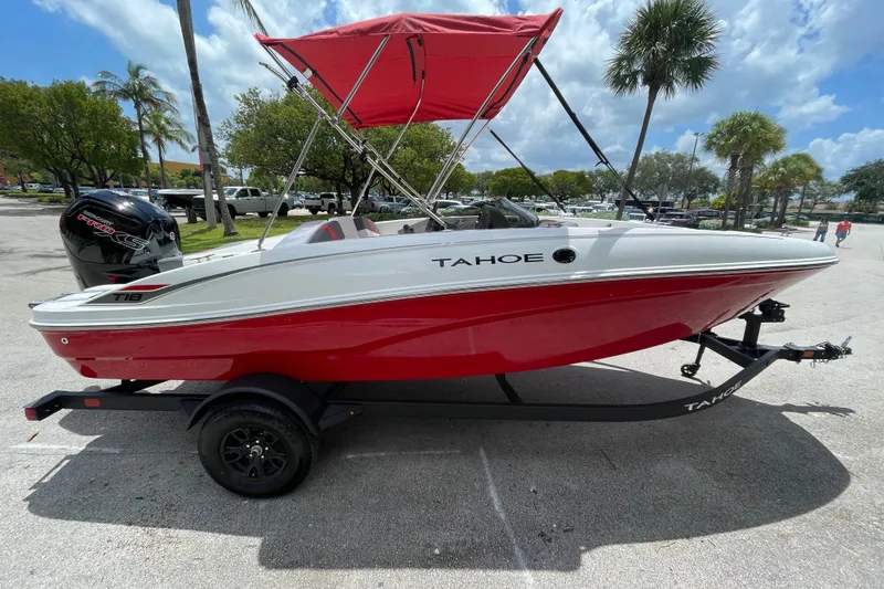 The Image of 2027 Tahoe T18 boat with red hull and canopy on trailer, parked outdoors. - 0