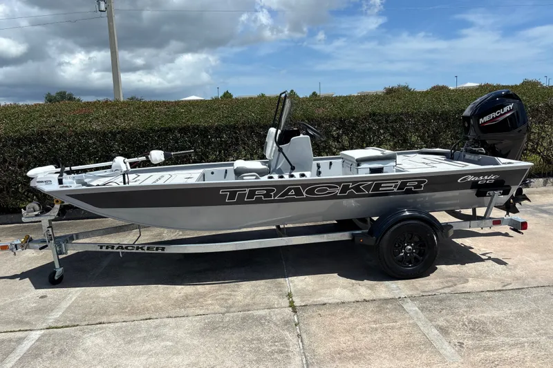 The Image of 2027 Tracker Bass Tracker Classic CC boat on trailer, parked outdoors under cloudy sky. - 0