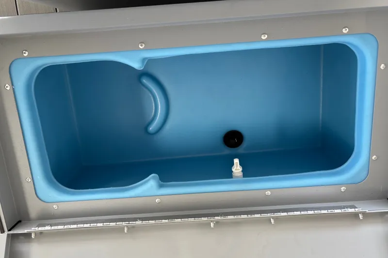 Slide: The Image of 2027 Tracker Bass Tracker Classic CC livewell, blue interior, open lid view. - 25