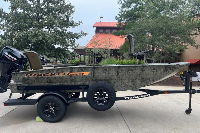 The Image of 2027 Tracker Grizzly 1553 Timber boat on trailer, outdoors with trees and building background. - 0