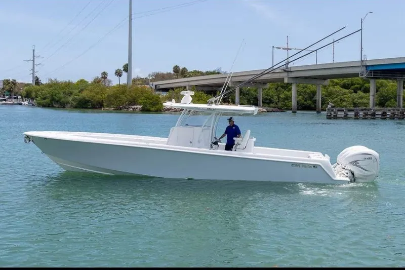The Image of 2023 Contender 39 ST boat cruising on a calm waterway near a bridge. - 0