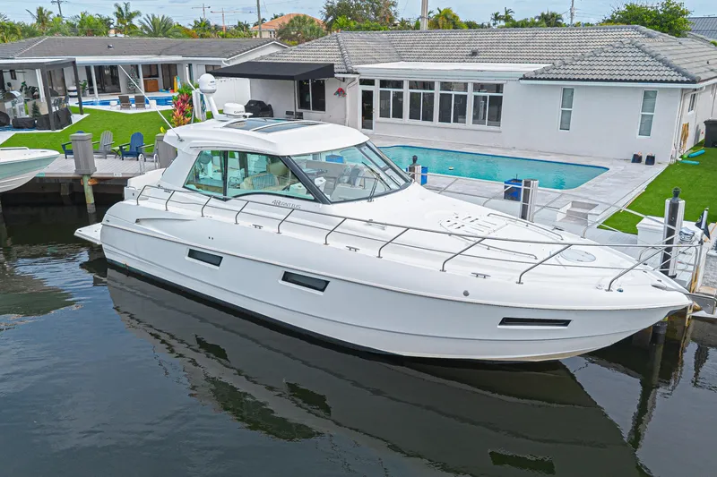 Slide: The Image of 2012 Cruisers Yachts 48 Cantius docked by a modern waterfront home with pool. - 1