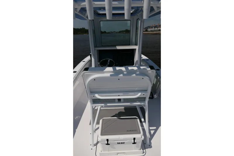 Slide: The Image of 2027 Blackfin 242 HB boat interior with helm and seating, on calm water. - 18