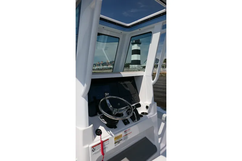 Slide: The Image of Interior view of 2027 Blackfin 242 HB boat cockpit with steering wheel and lighthouse in background. - 15